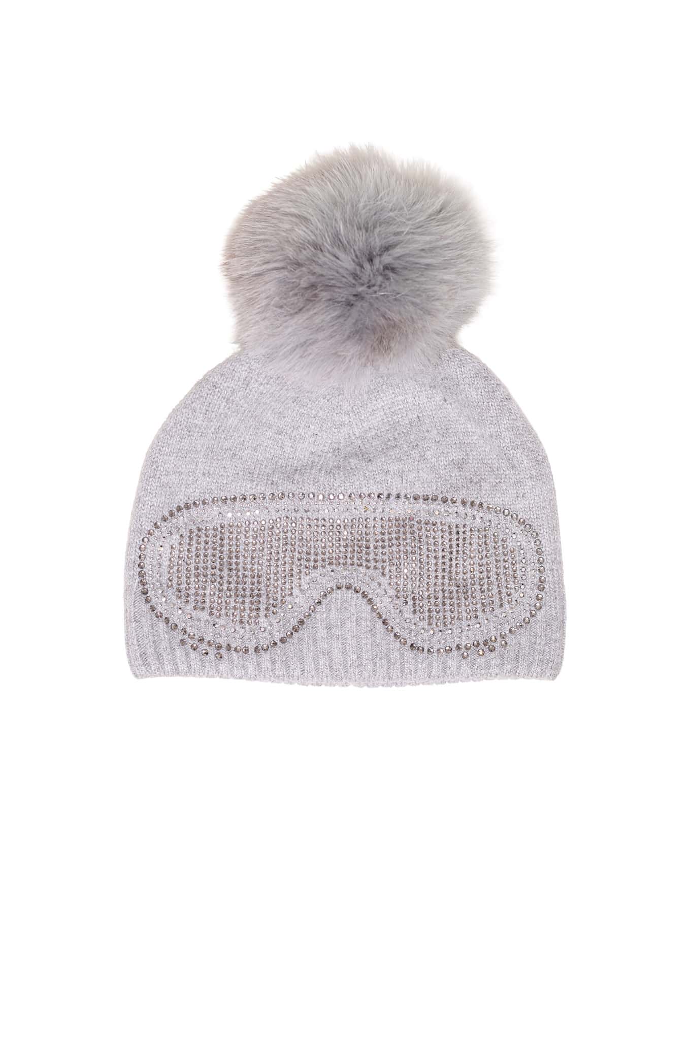 A grey beanie with ski goggles and a fox pom pom sitting atop a white background.
