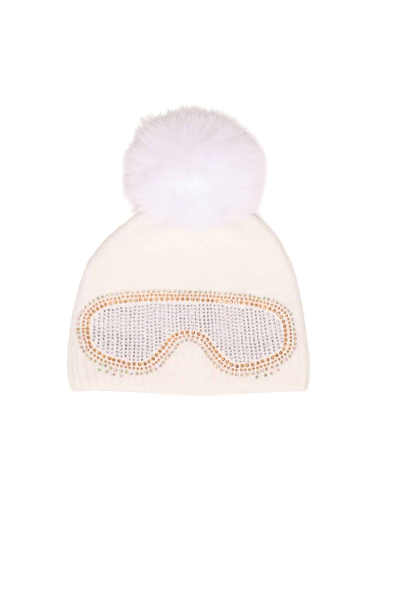 A white beanie with ski goggles and a fox pom pom sitting atop a white background.