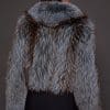 the back of a woman in a blue and grey fur jacket against a grey background