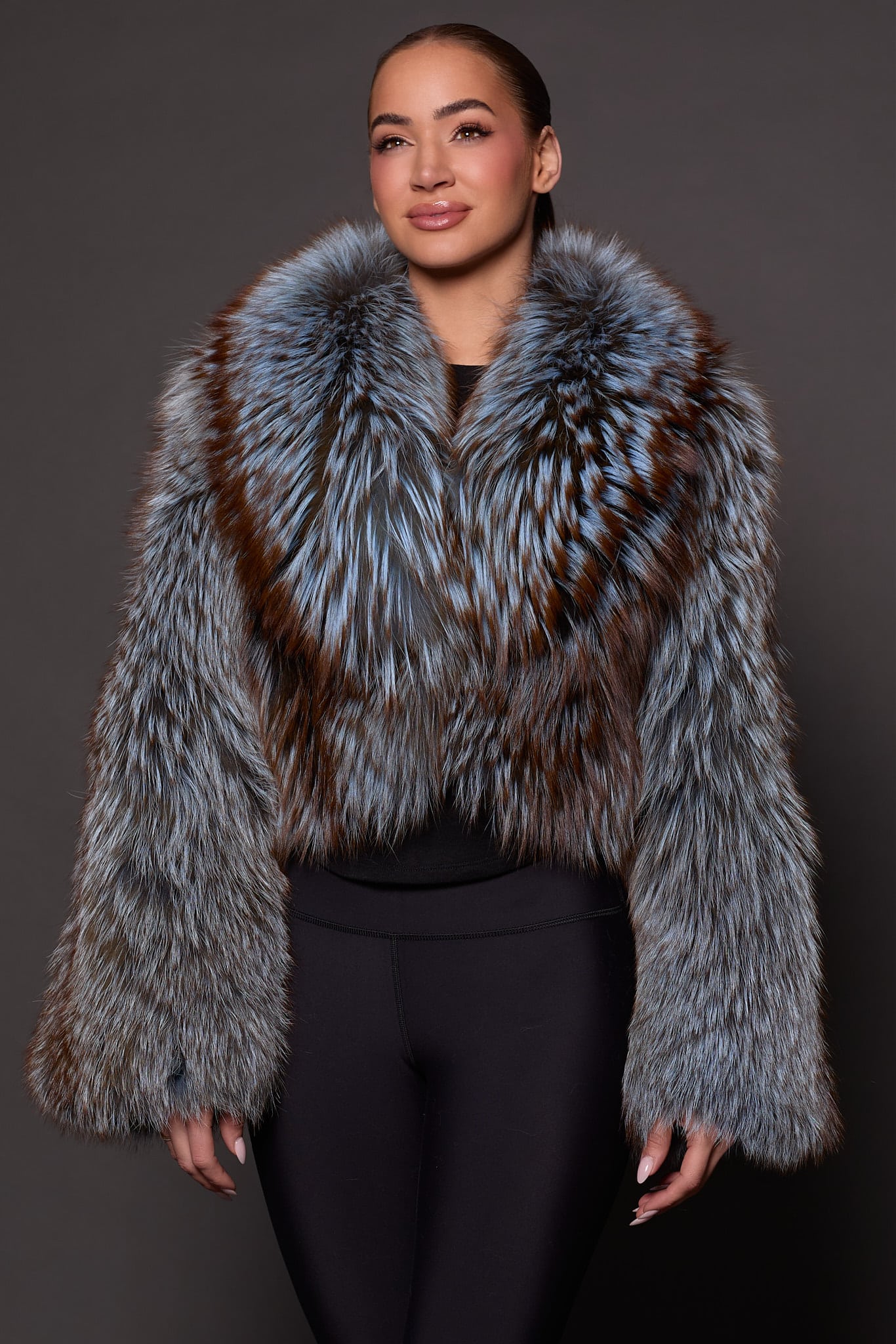the front of a woman in a blue and grey fur jacket against a grey background
