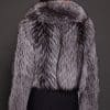 the back of a woman in a silver fur jacket against a grey background