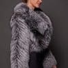 the side profile of a a woman in a silver fur jacket against a grey background