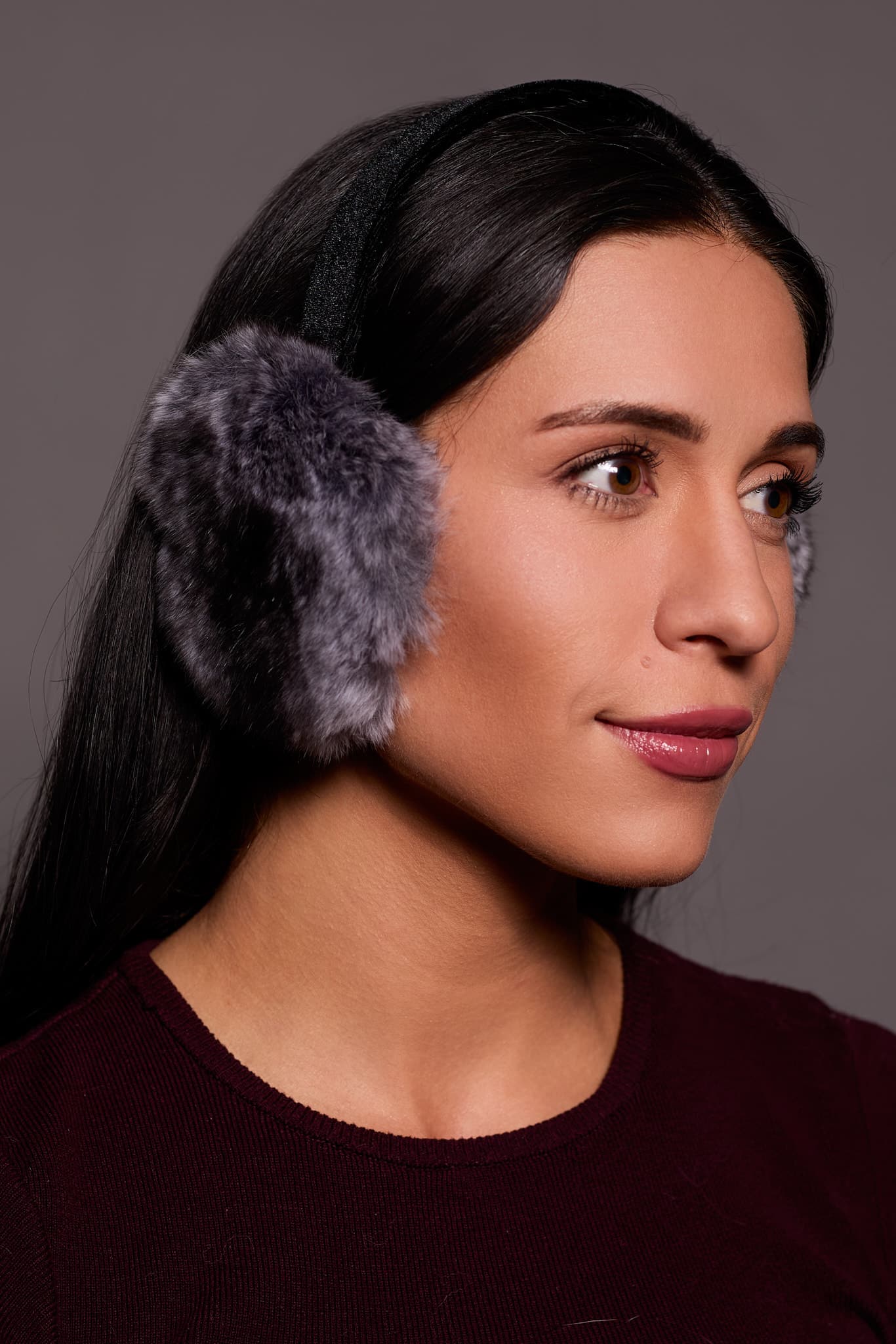 woman wearing grey earmuffs against a grey backdrop