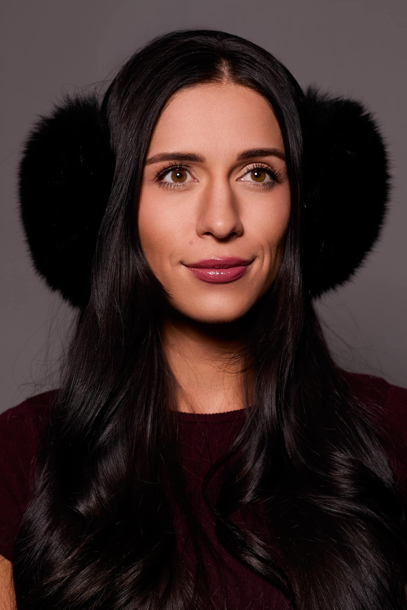 woman wearing black earmuffs against a grey background