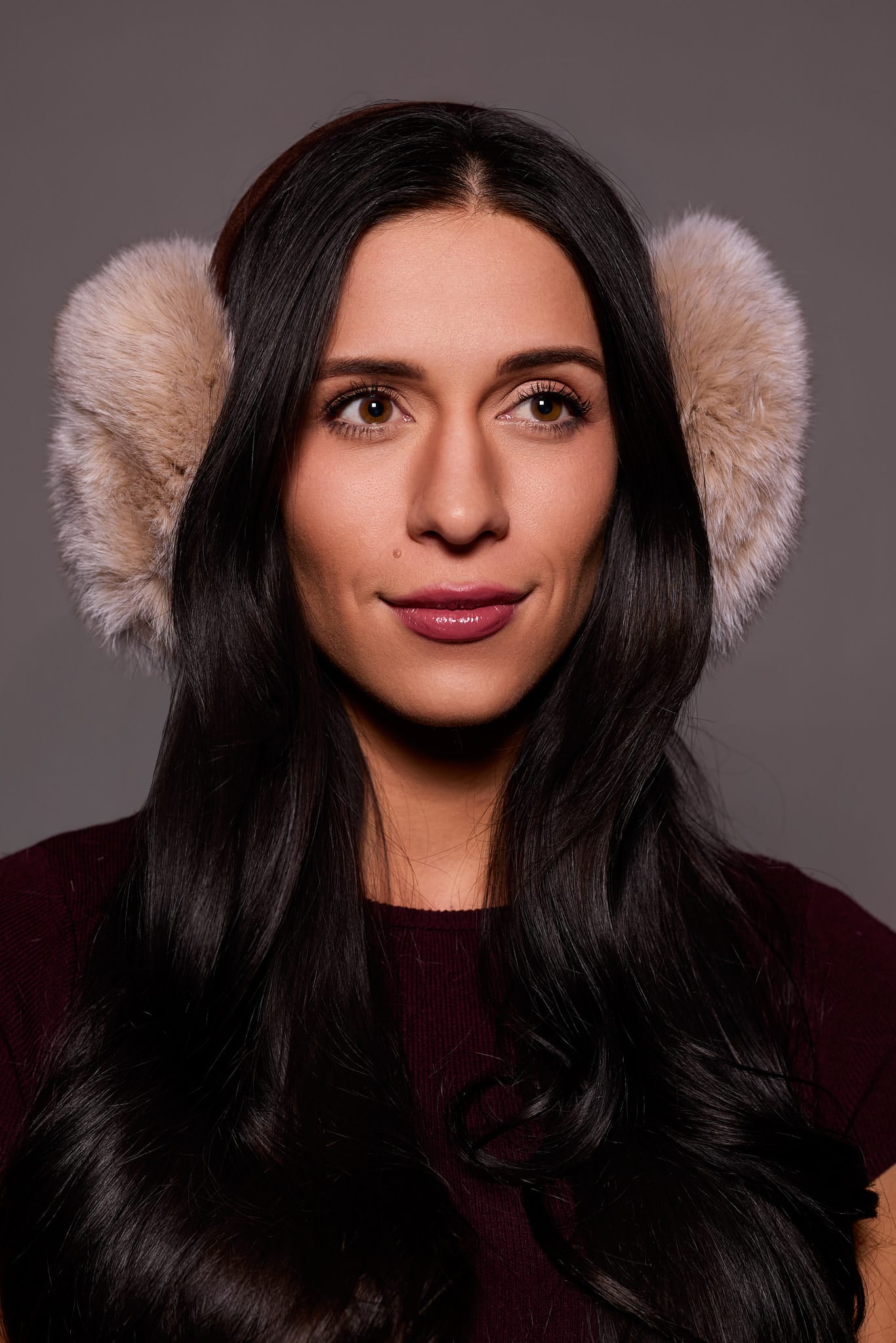 woman wearing beige earmuffs against a grey background
