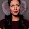 woman wearing silver earmuffs against a grey background