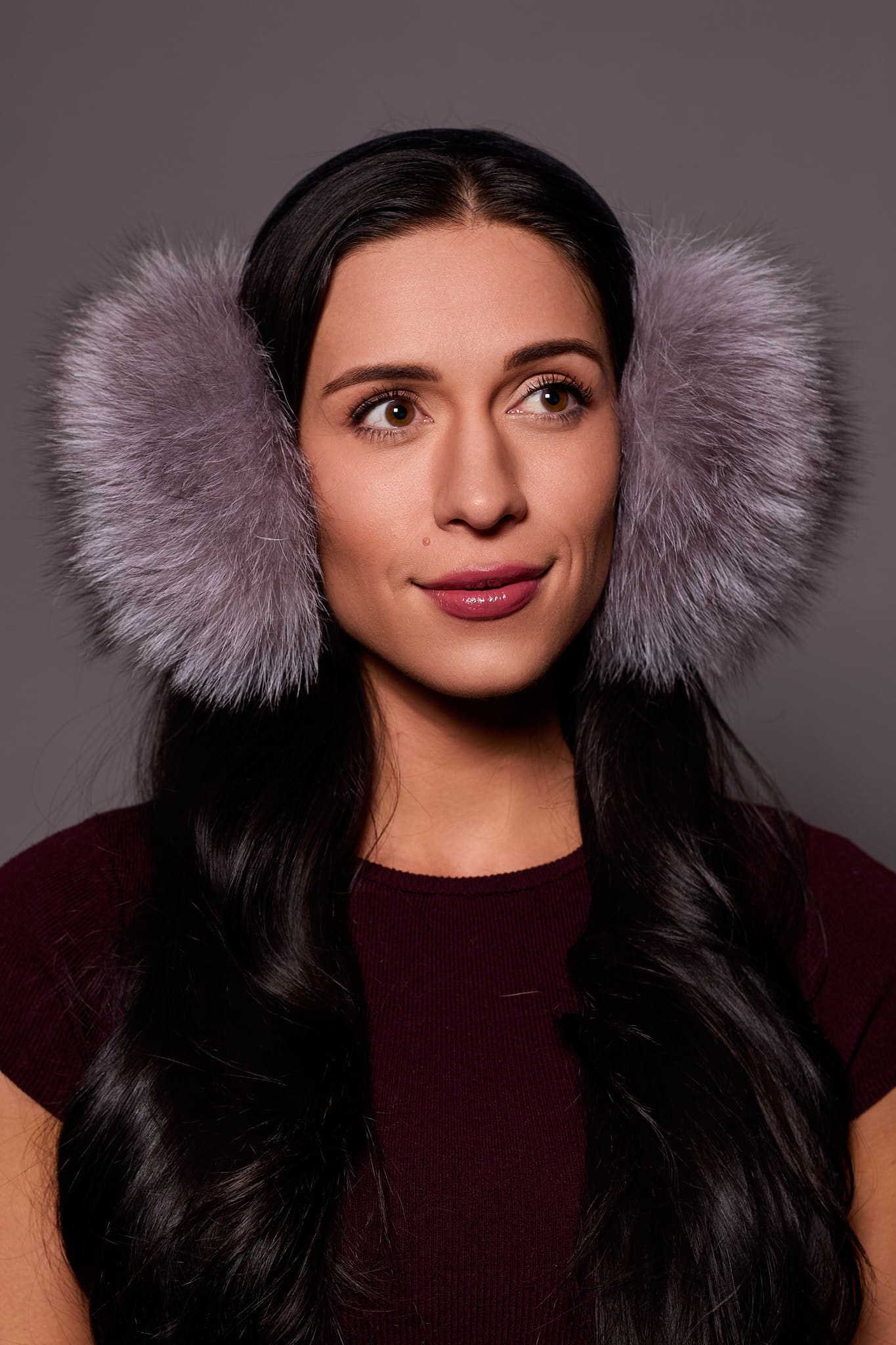 woman wearing silver earmuffs against a grey background