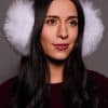 woman wearing white earmuffs against a grey background