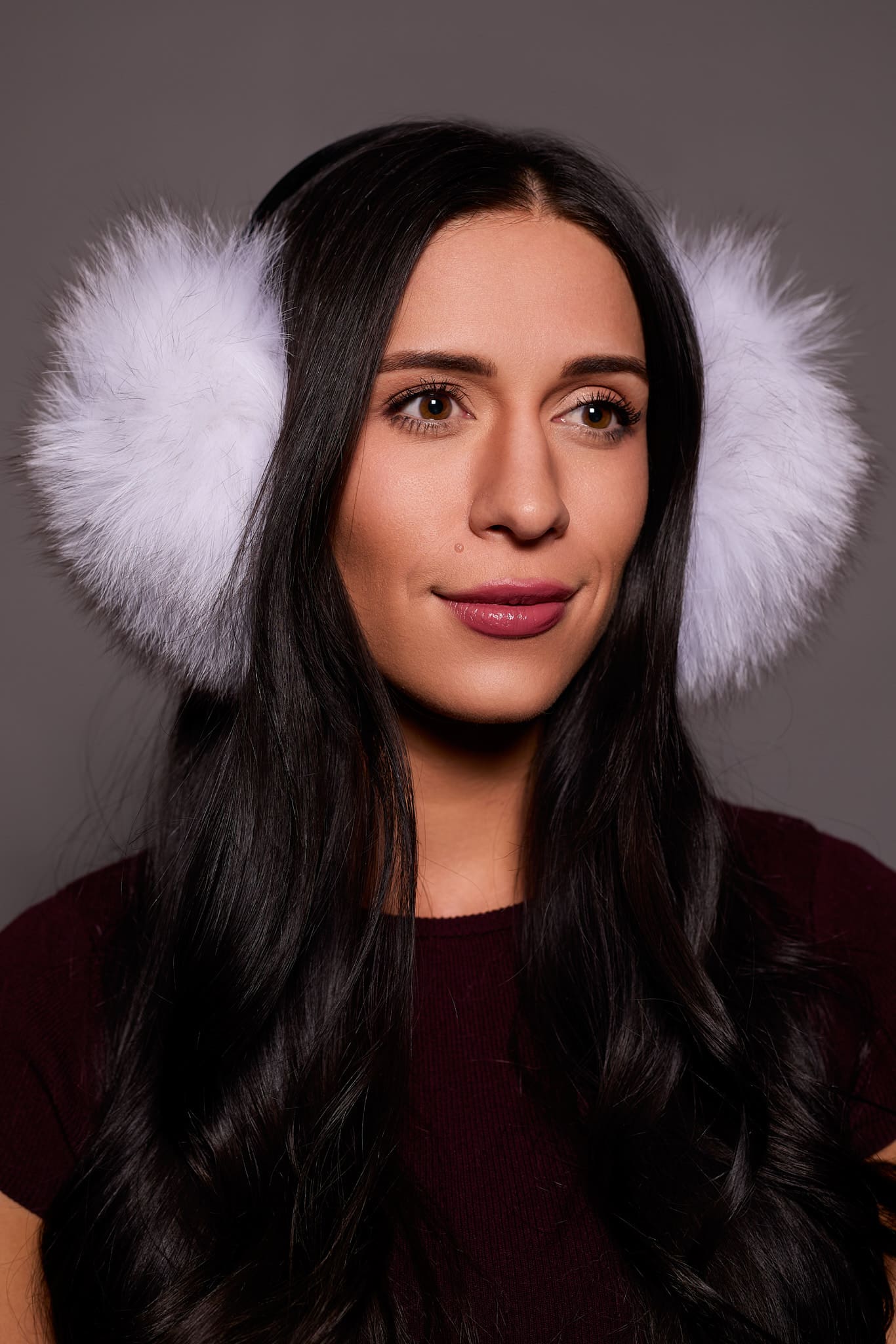 woman wearing white earmuffs against a grey background