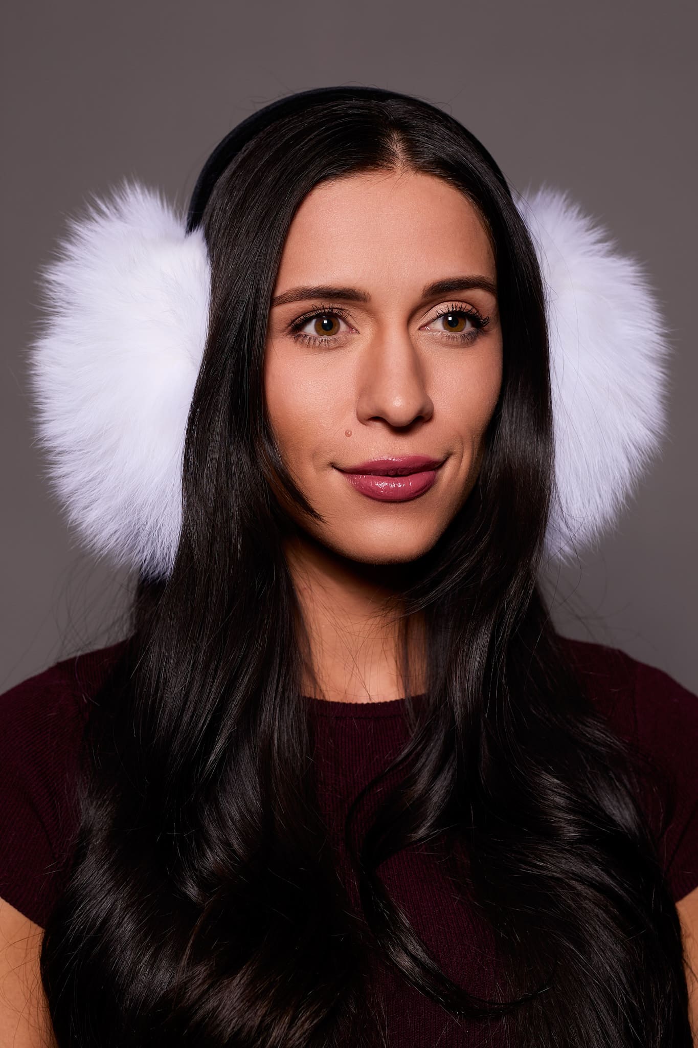 woman wearing white earmuffs against a grey background