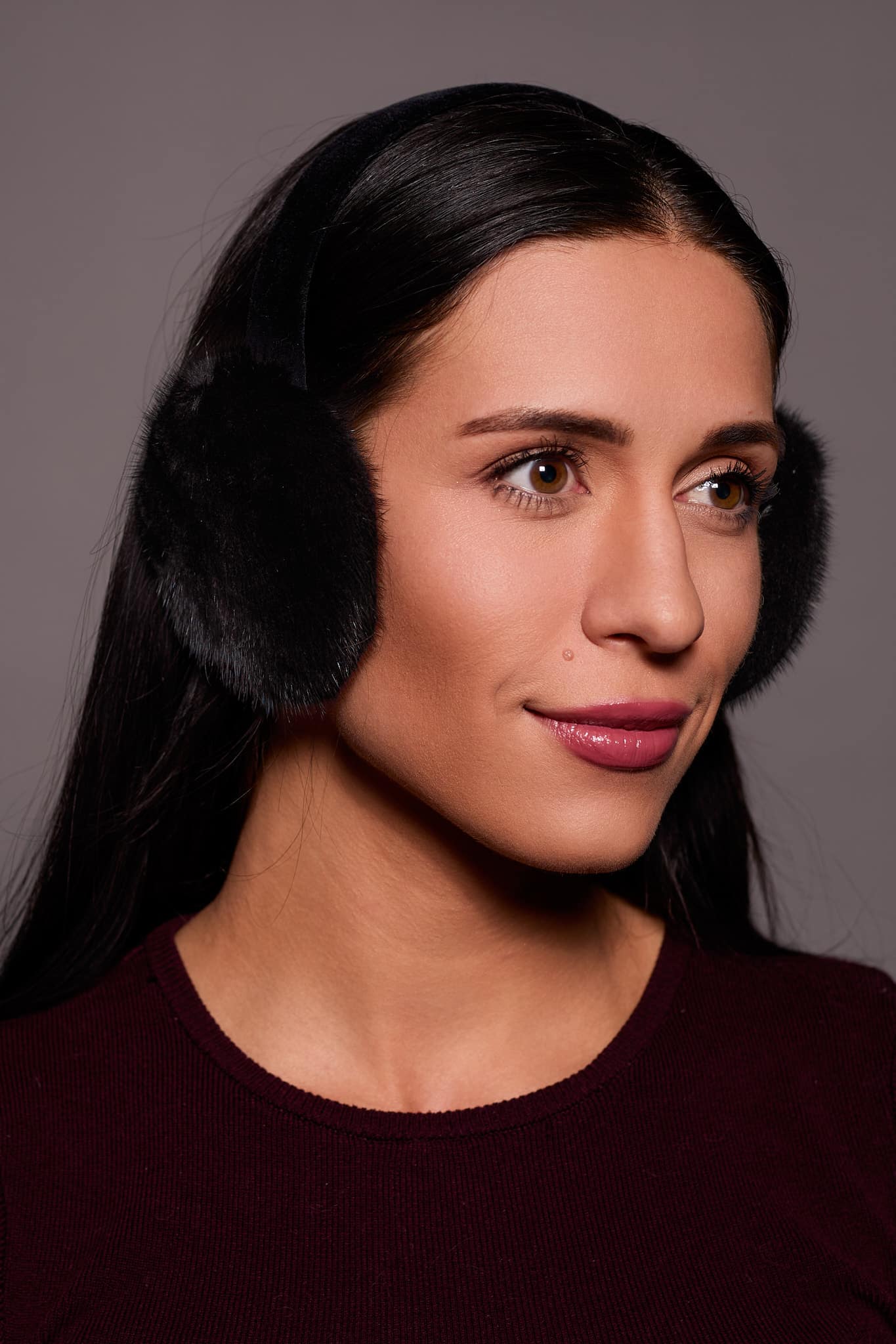 woman in black earmuffs against a grey background