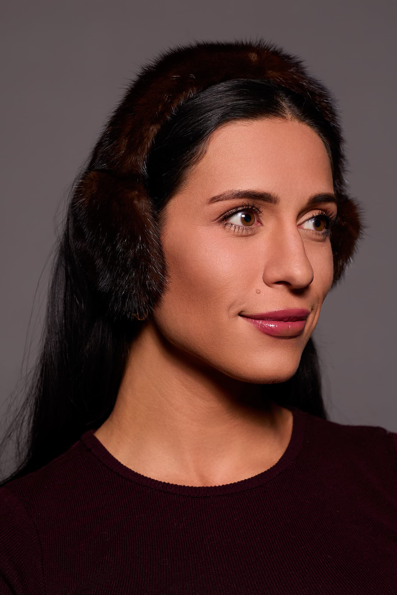 woman wearing brown earmuffs against a grey background