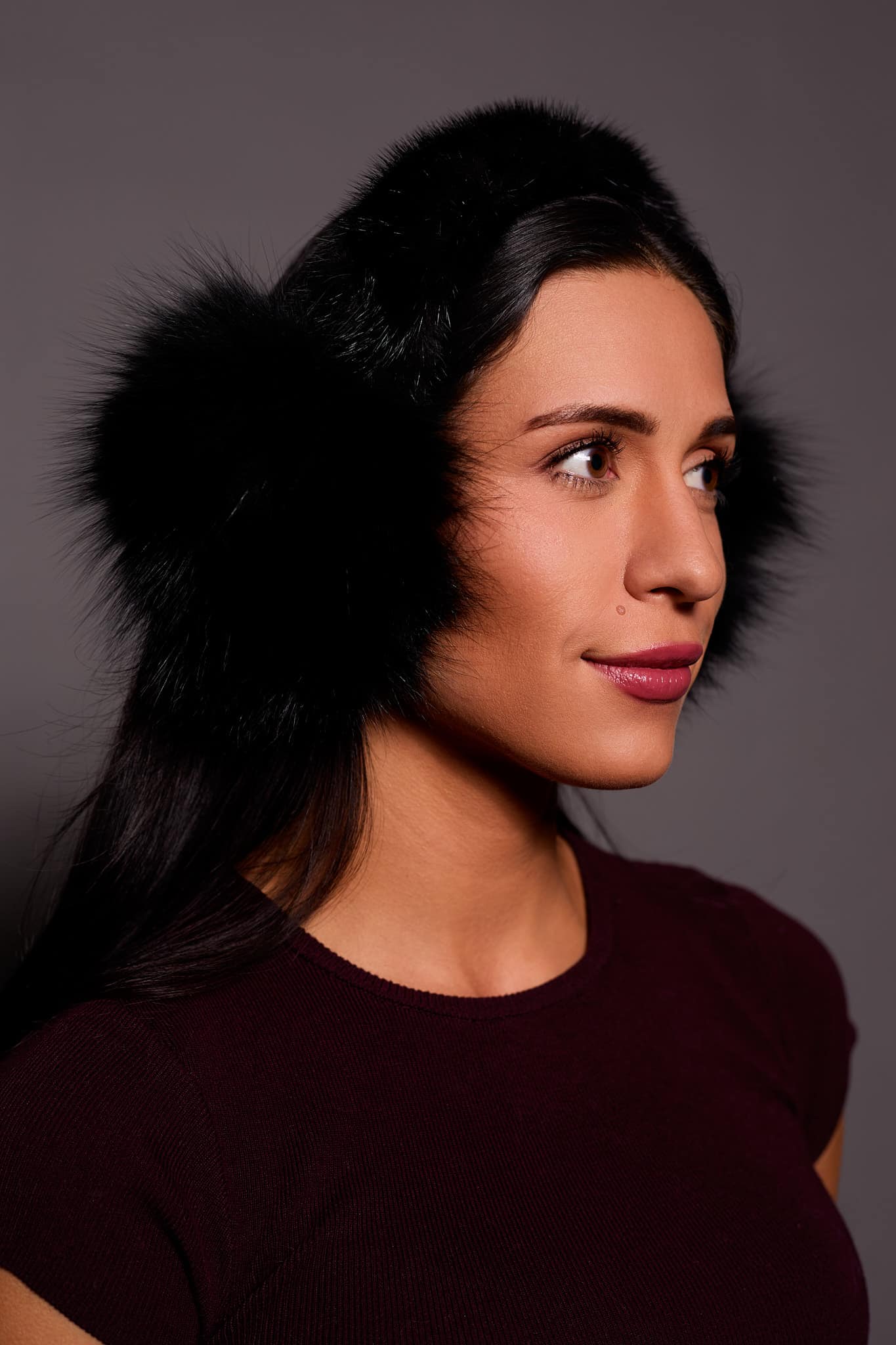 woman wearing black earmuffs against a grey background