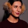 woman wearing brown earmuffs against a grey background