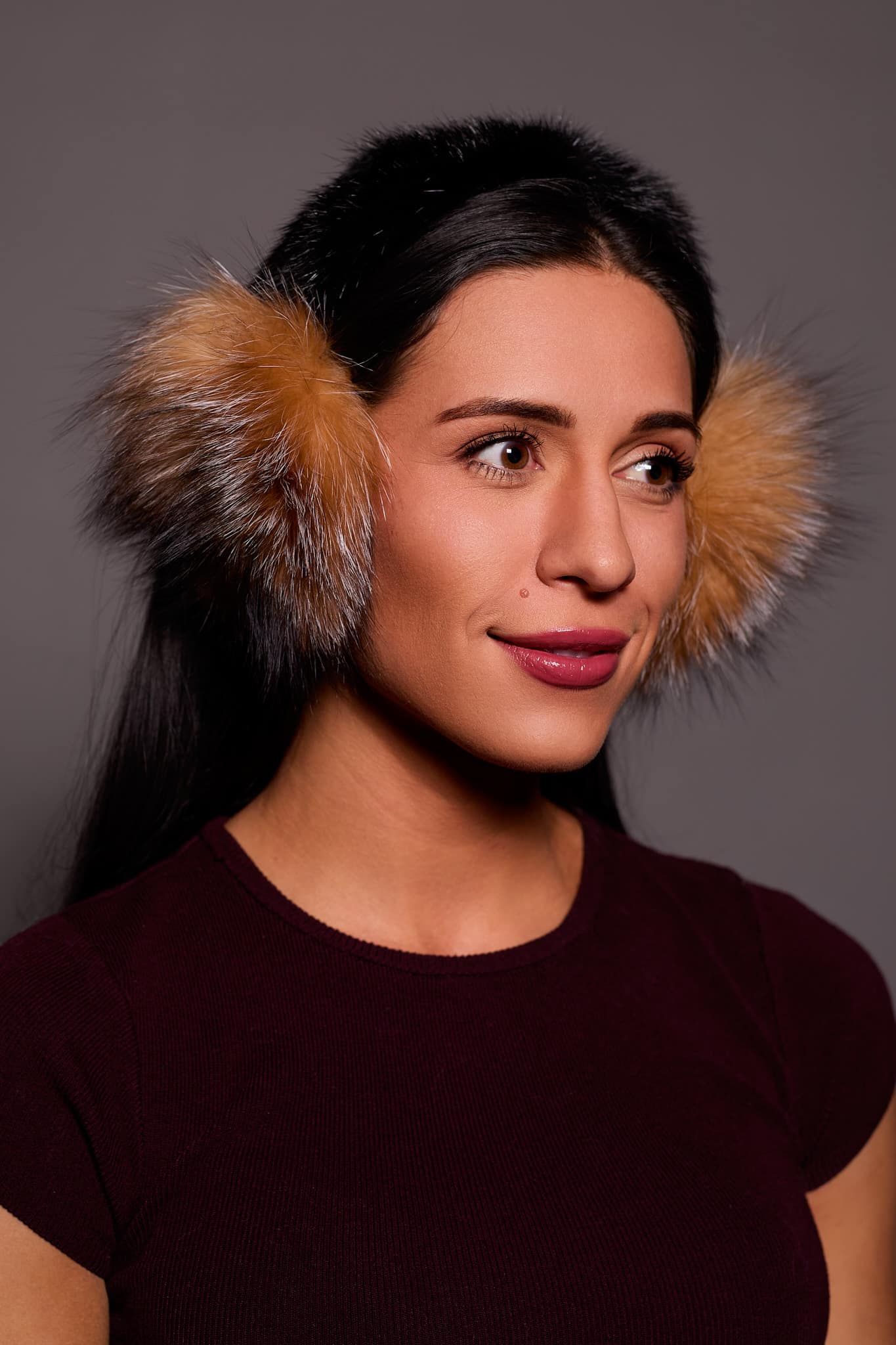 woman wearing brown earmuffs against a grey background