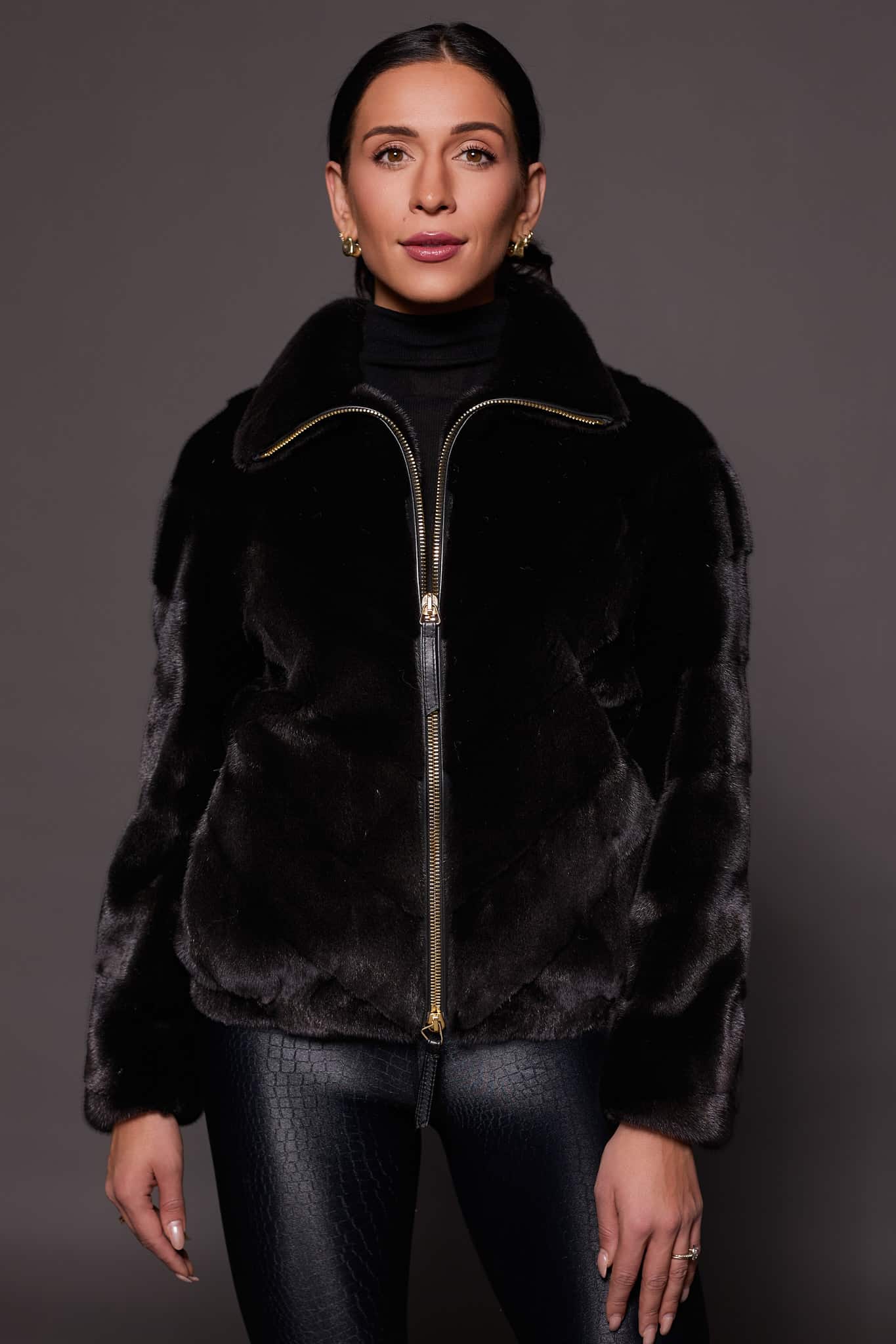 the front of a woman in a black mink jacket against a grey background