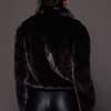 the back of a woman in a black mink jacket against a grey background