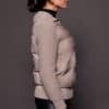 the side of a woman in a grey jacket against a grey background