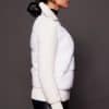 the side of a woman in a white jacket against a grey background