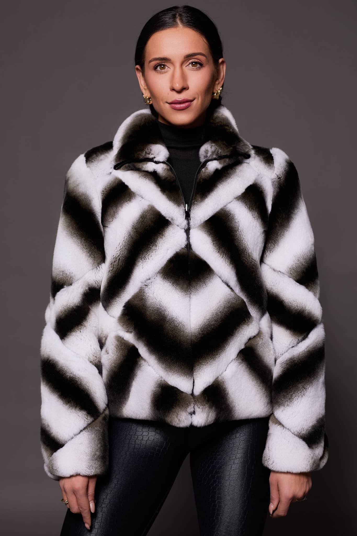 the front of a woman in a black and white abstract pattern jacket against a grey background