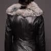 the back of a woman in a black leather jacket with a brown fur trim against a dark grey background