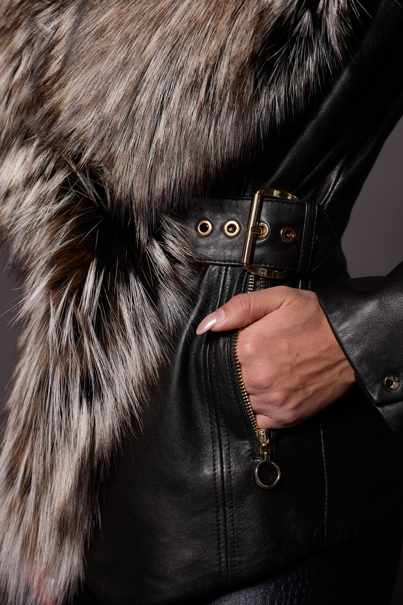 up close image of the hand of a woman in the pocket of a black leather jacket with fur trim