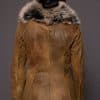 the back of a woman in a brown leather jacket with fur against a grey backdrop