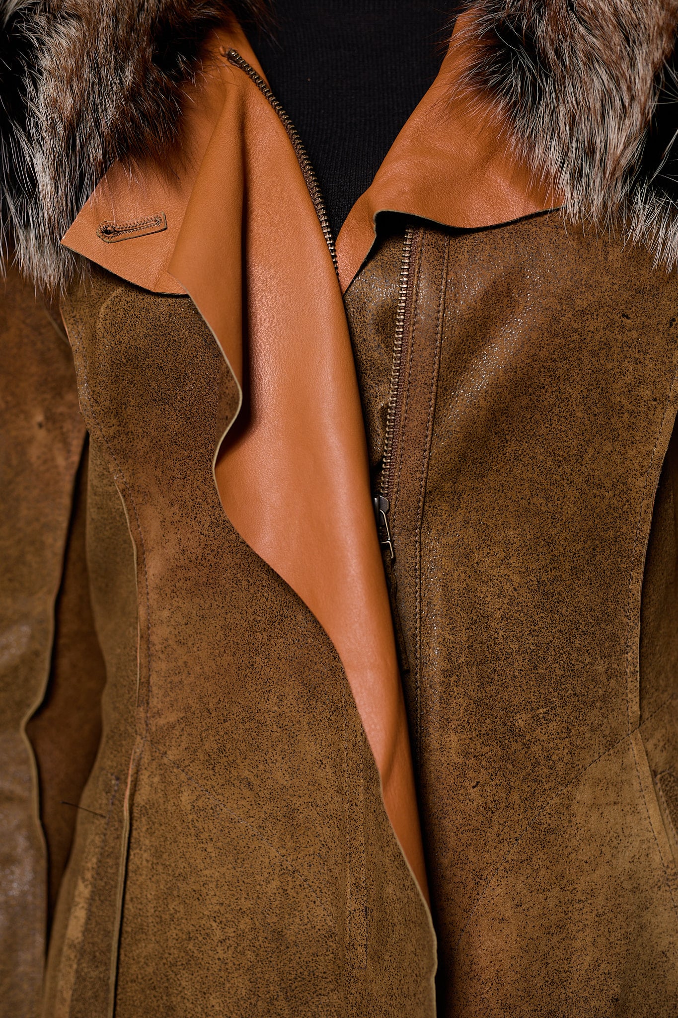 close up detailed image of a woman in a brown leather jacket with fur against a grey backdrop