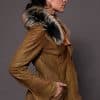the side of a woman in a brown leather jacket with fur against a grey backdrop