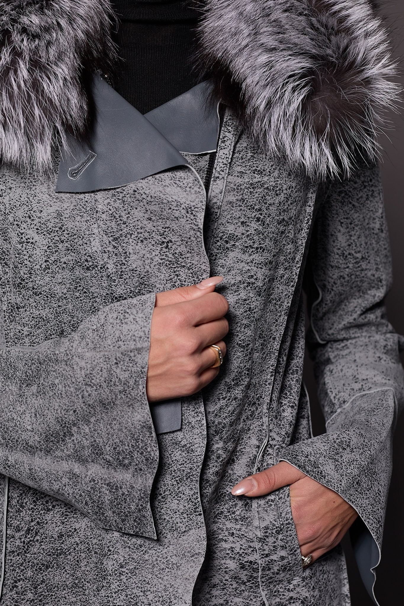 close up detailed image of a woman in a grey leather jacket with fur against a grey backdrop