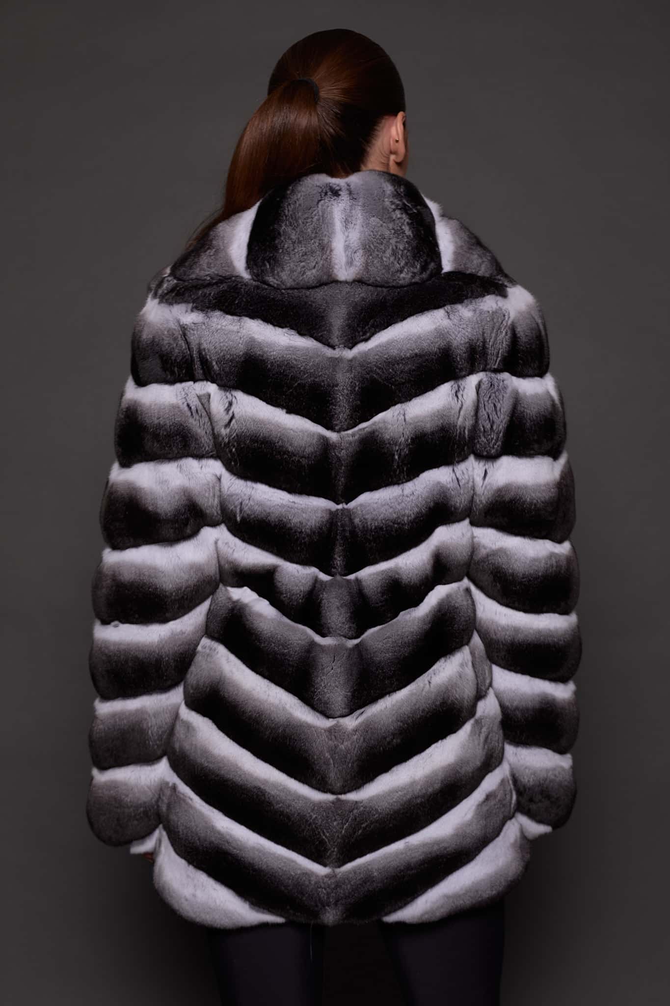 CARRIE CHINCHILLA NATURAL BACK the back of a woman in black and white fur coat against a grey background