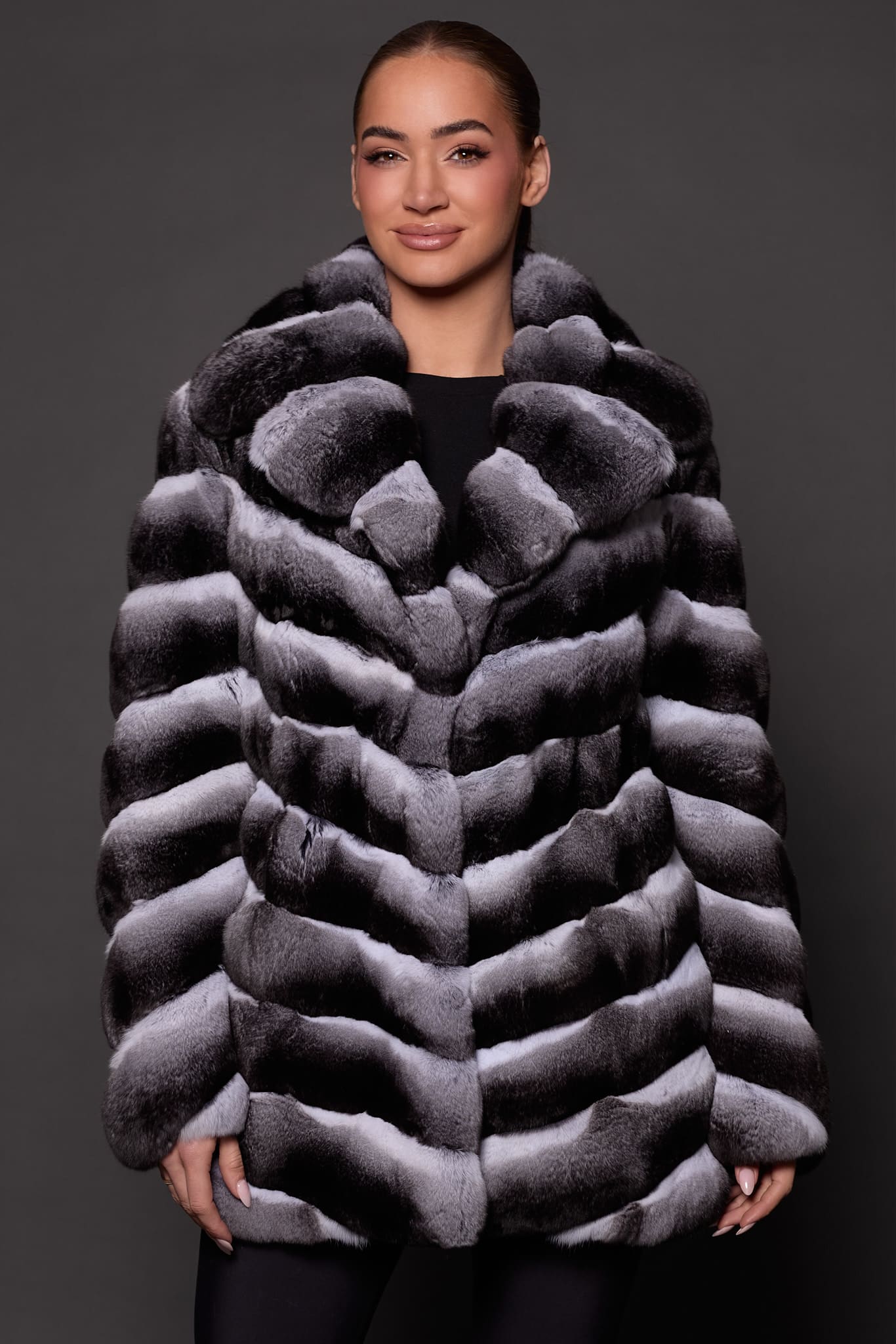 the front of a woman in black and white fur coat against a grey background