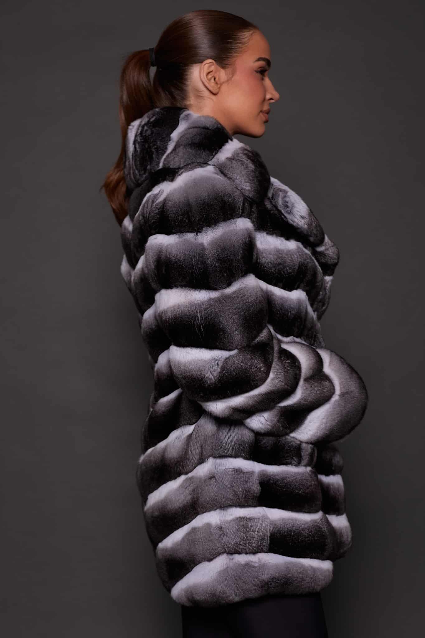 CARRIE CHINCHILLA NATURAL SIDE the side of a woman in black and white fur coat against a grey background