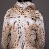 the back of a woman in a lynx fur coat against a grey background