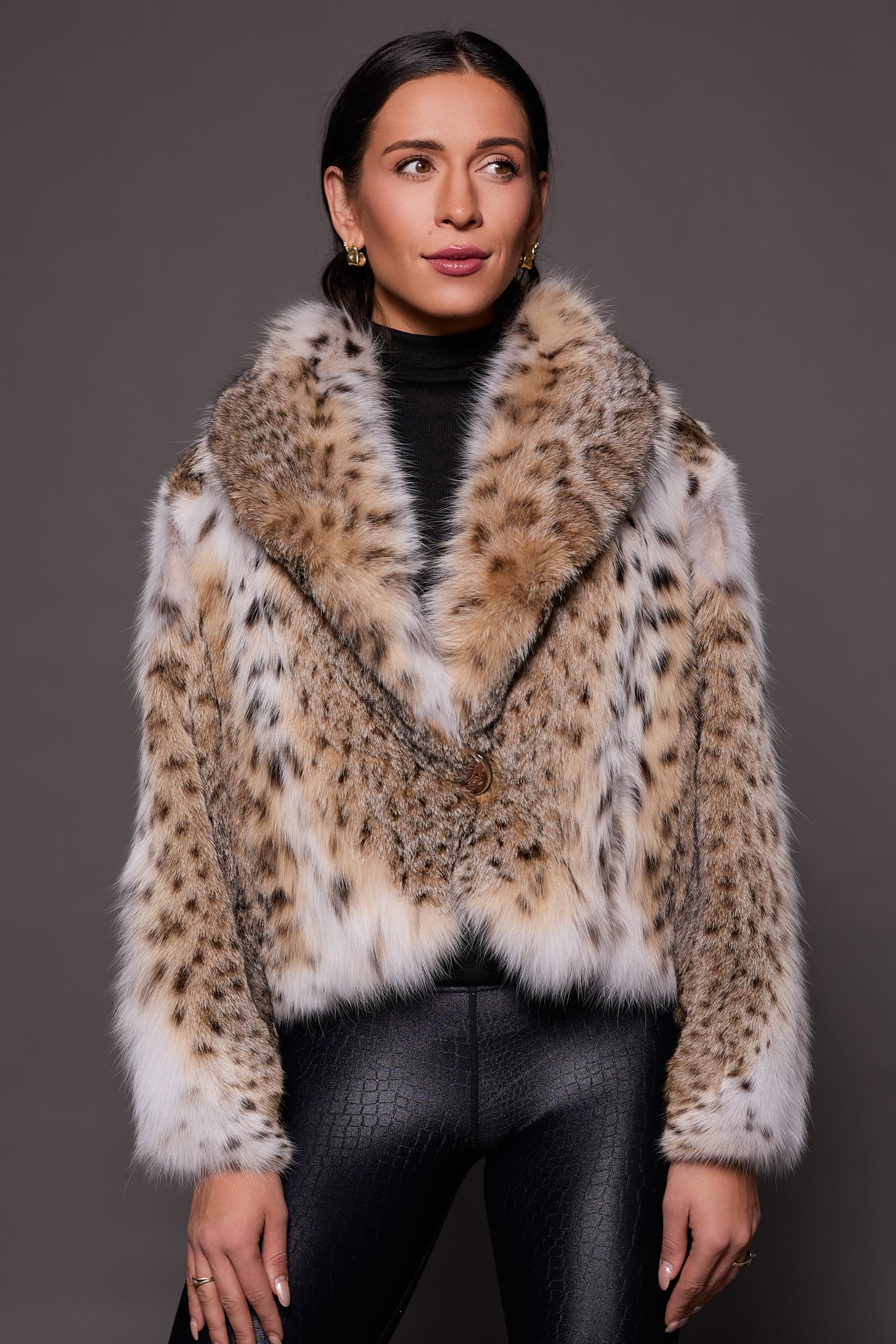 the front of a woman in a lynx fur coat against a grey background