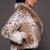 the side of a woman in a lynx fur coat against a grey background