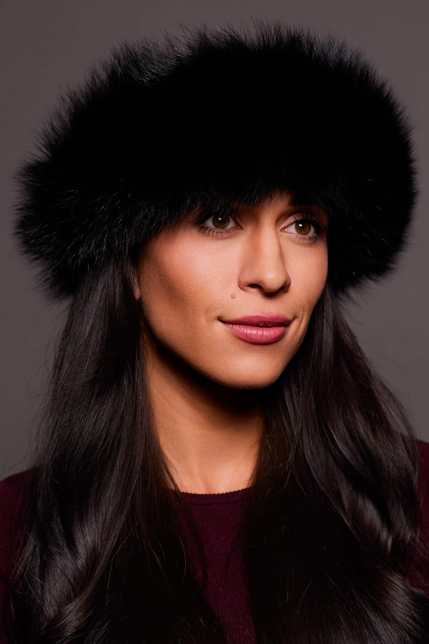 Frontal portrait shot of a woman wearing a black colored fox fur headband.