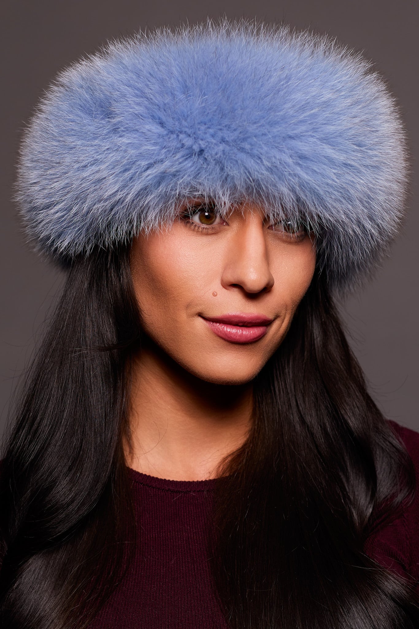 Frontal portrait shot of a woman wearing a blue colored fox fur headband.