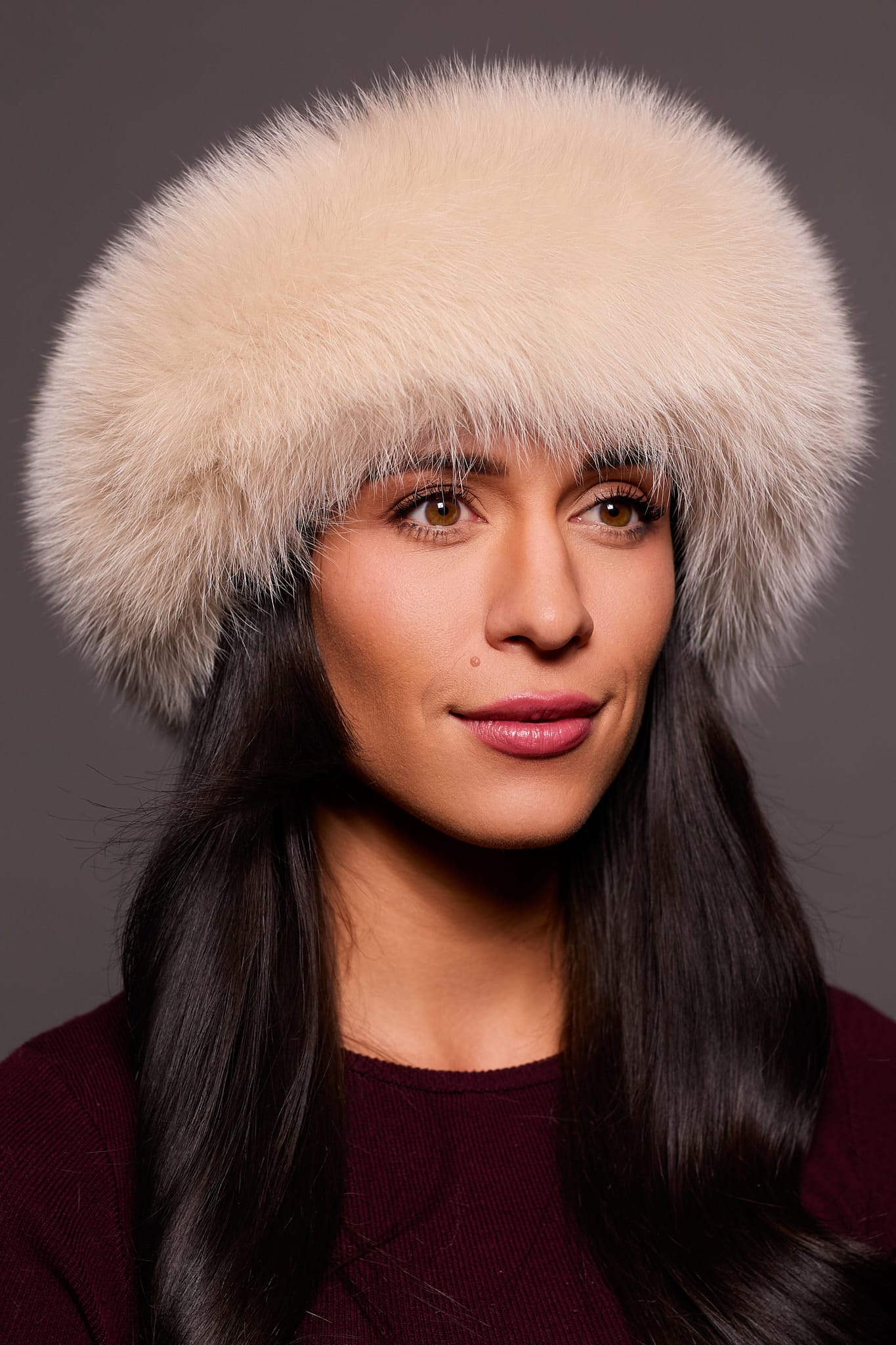 Frontal portrait shot of a woman wearing a blush colored fox fur headband.