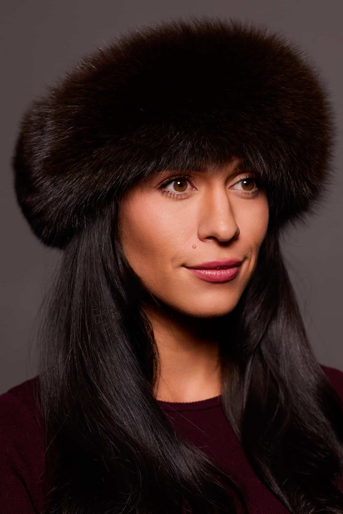 Frontal portrait shot of a woman wearing a brown colored fox fur headband.