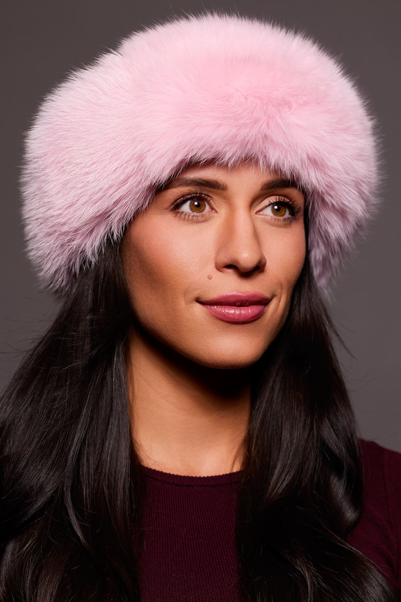Frontal portrait shot of a woman wearing a pink colored fox fur headband.