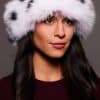 Frontal portrait shot of a woman wearing a white and black spotted fox fur headband.