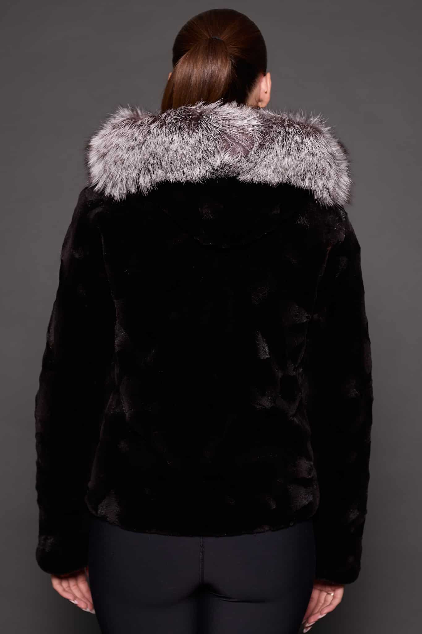 GIA MINK BLACK SILVER FOX BACK the back of a woman in a black and grey fur jacket against a grey background
