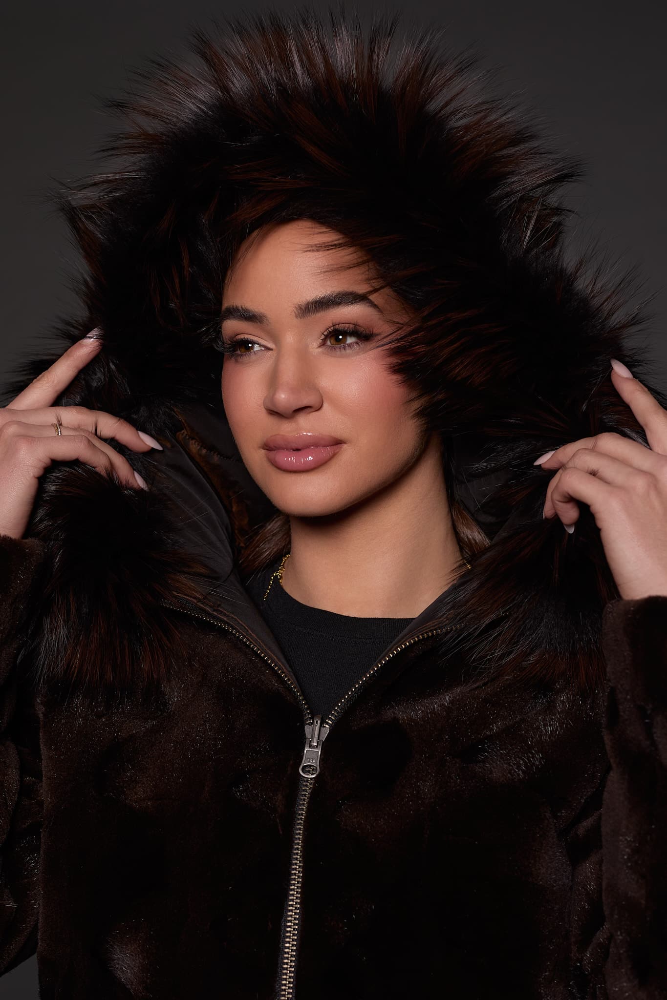 GIA MINK ESPRESSO SILVER FOX HOOD up close headshot of a woman in a brown fur jacket with the hood over her head against a grey background