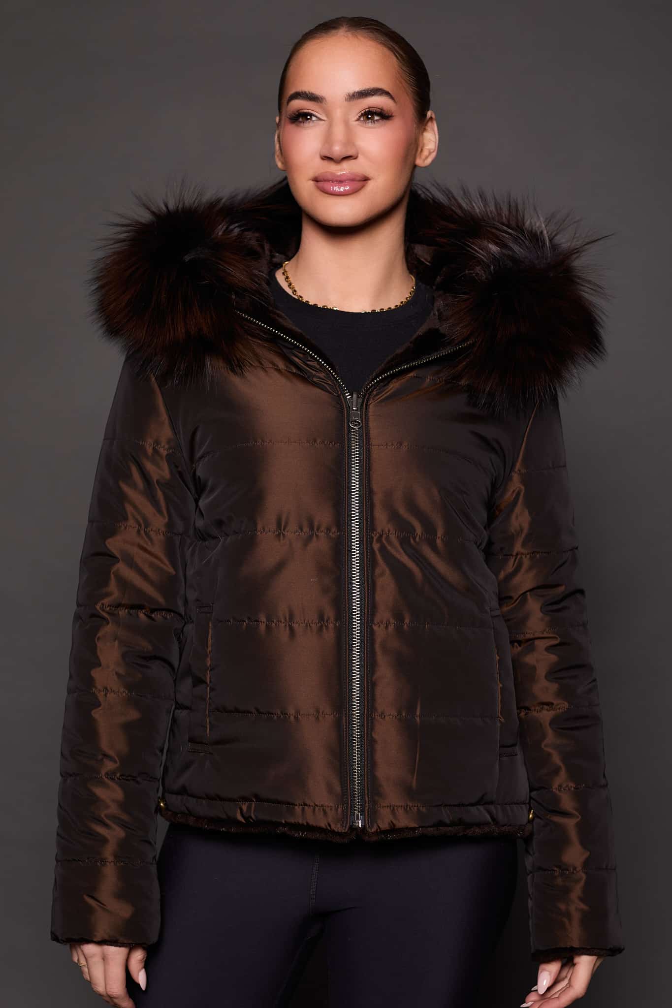 the front of a woman in a brown fur jacket against a grey background