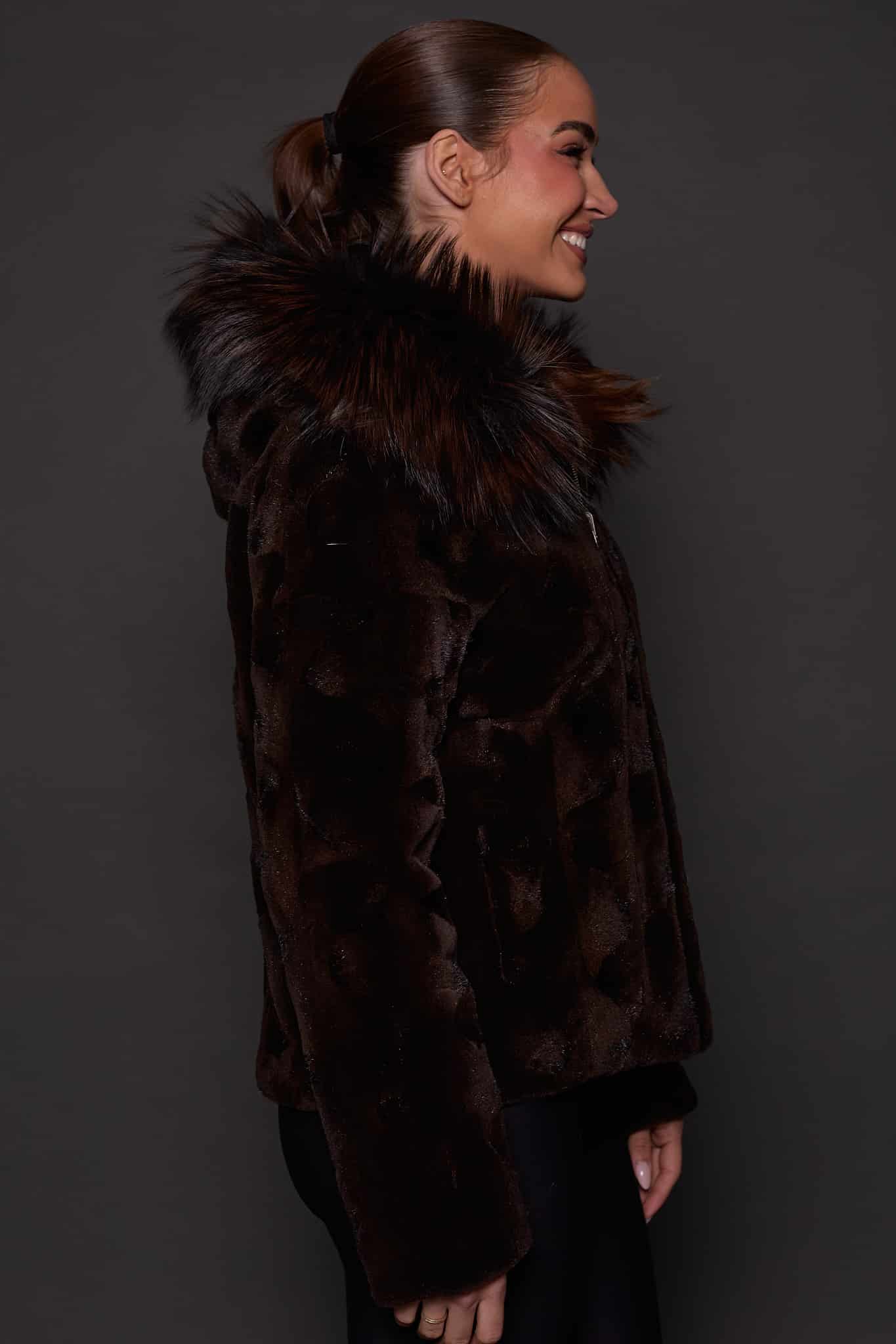 GIA MINK ESPRESSO SILVER FOX SIDE the side of a woman in a brown fur jacket against a grey background