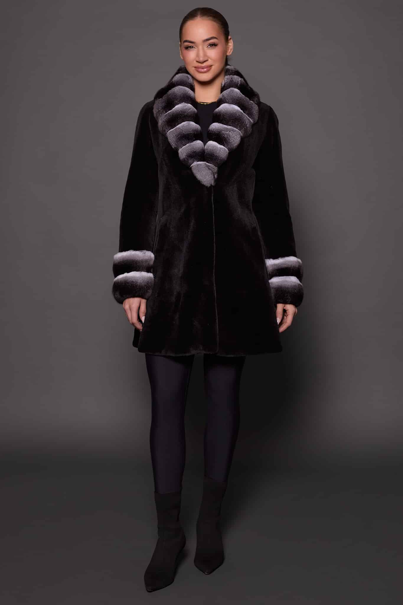 Frontal view of a woman wearing a sheared mink fur coat standing in front of a grey background.