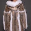 Rear view of a woman wearing a lynx fur coat with the hood down facing a grey background.