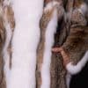 Close-up details of a lynx fur coat with a woman's left hand in the coat's left pocket.