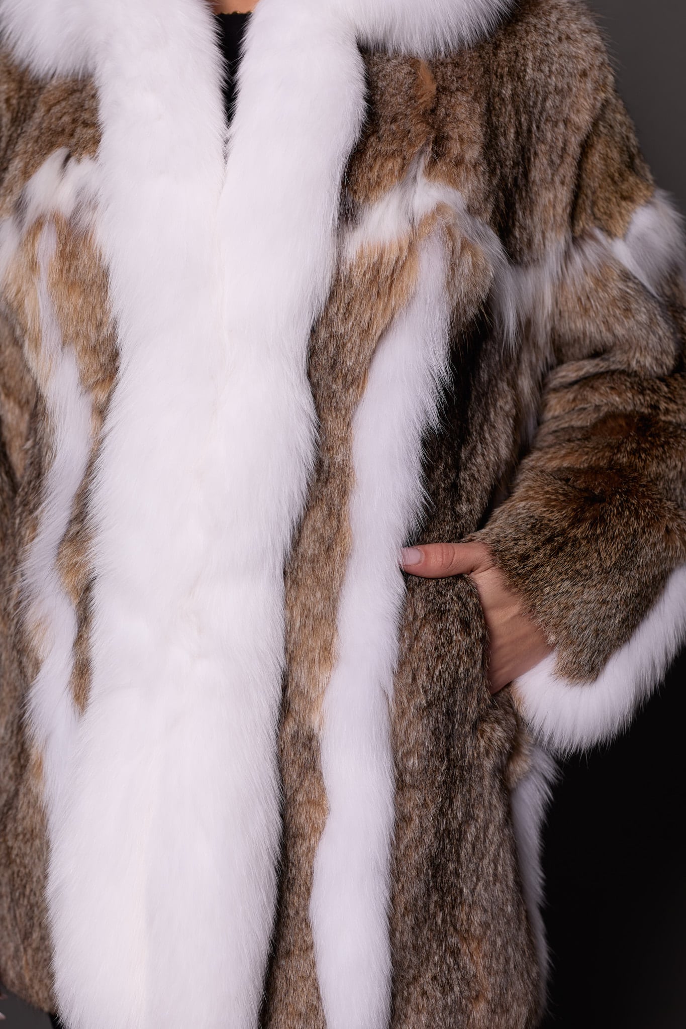 Close-up details of a lynx fur coat with a woman's left hand in the coat's left pocket.